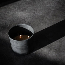 Load image into Gallery viewer, Burning candle in handcrafted  porcelain vessel with smoky tobacco and tonka bean fragrance